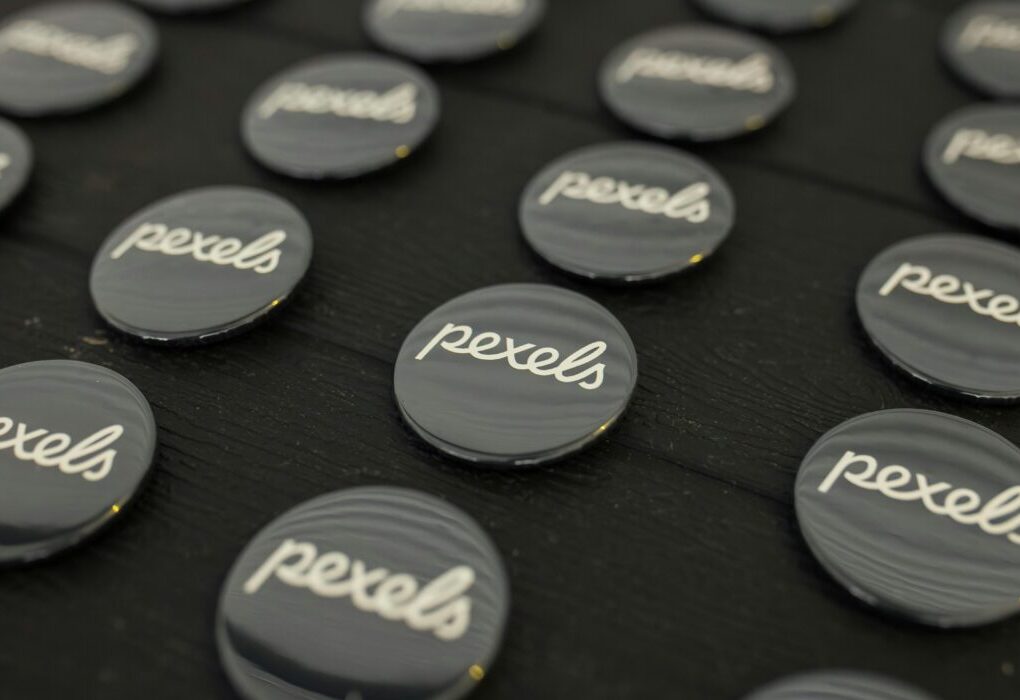 A close-up view of multiple Pexels logo buttons arranged neatly on a dark surface. — Photo by Matheus Bertelli on Pexels