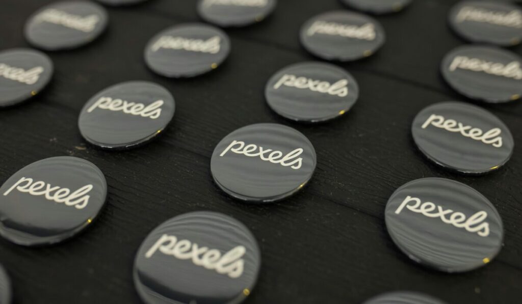 A close-up view of multiple Pexels logo buttons arranged neatly on a dark surface. — Photo by Matheus Bertelli on Pexels