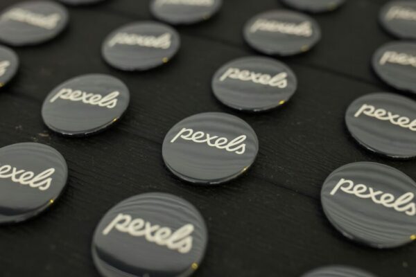 A close-up view of multiple Pexels logo buttons arranged neatly on a dark surface. — Photo by Matheus Bertelli on Pexels