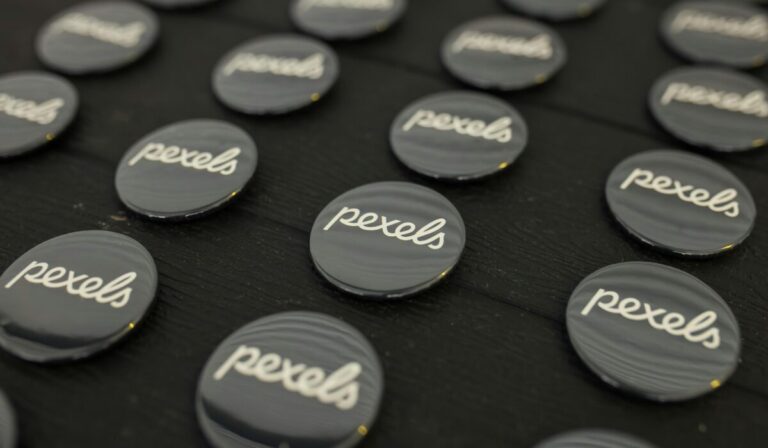 A close-up view of multiple Pexels logo buttons arranged neatly on a dark surface. — Photo by Matheus Bertelli on Pexels