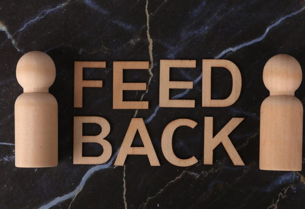 Wooden letters spelling 'Feedback' with peg-like figures on marble background. &mdash; Photo by Ann H on Pexels