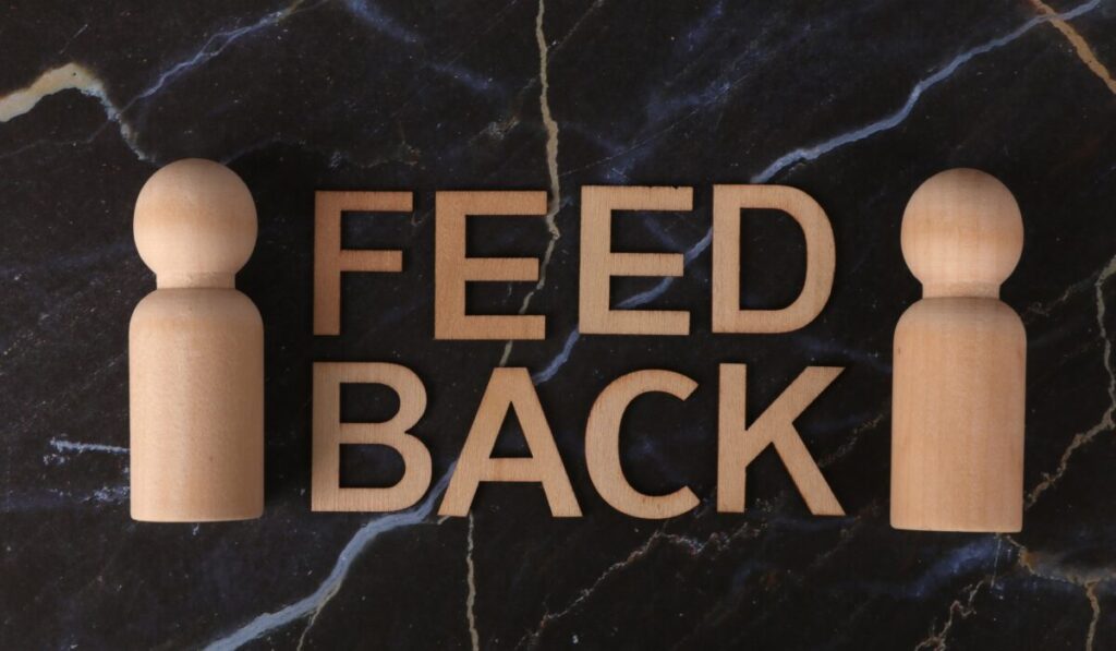 Wooden letters spelling 'Feedback' with peg-like figures on marble background. &mdash; Photo by Ann H on Pexels