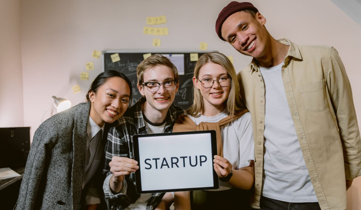 A diverse group of young professionals in a startup office, smiling and holding a sign. — Photo by Tima Miroshnichenko on Pexels