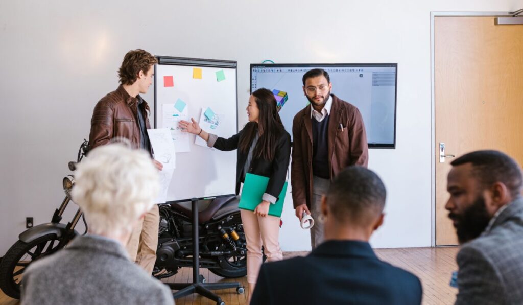 A multicultural team collaborates in an office, presenting ideas using a whiteboard and digital screen. — Photo by RDNE Stock project on Pexels