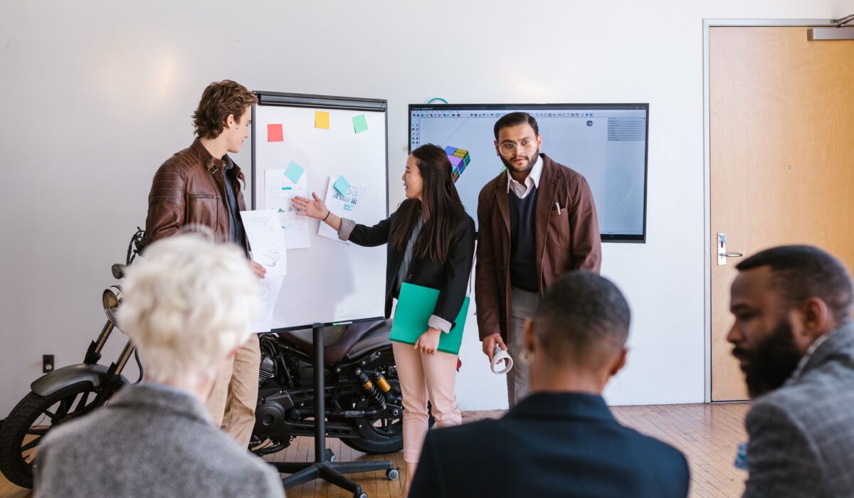 A multicultural team collaborates in an office, presenting ideas using a whiteboard and digital screen. — Photo by RDNE Stock project on Pexels