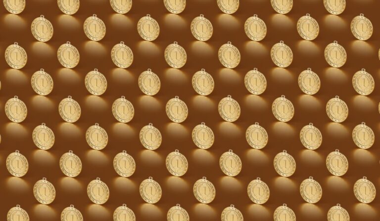 Multiple gold medals arranged in a repeating pattern on a brown backdrop. &mdash; Photo by DS stories on Pexels
