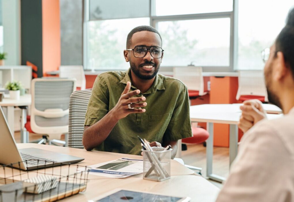 Two professionals engage in a casual meeting in a modern office setting. &mdash; Photo by Edmond Dant&egrave;s on Pexels