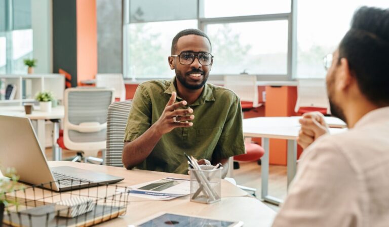 Two professionals engage in a casual meeting in a modern office setting. &mdash; Photo by Edmond Dant&egrave;s on Pexels