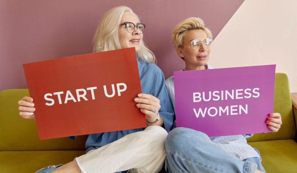 Two women on a sofa holding signs promoting startup and business women. — Photo by Darina Belonogova on Pexels