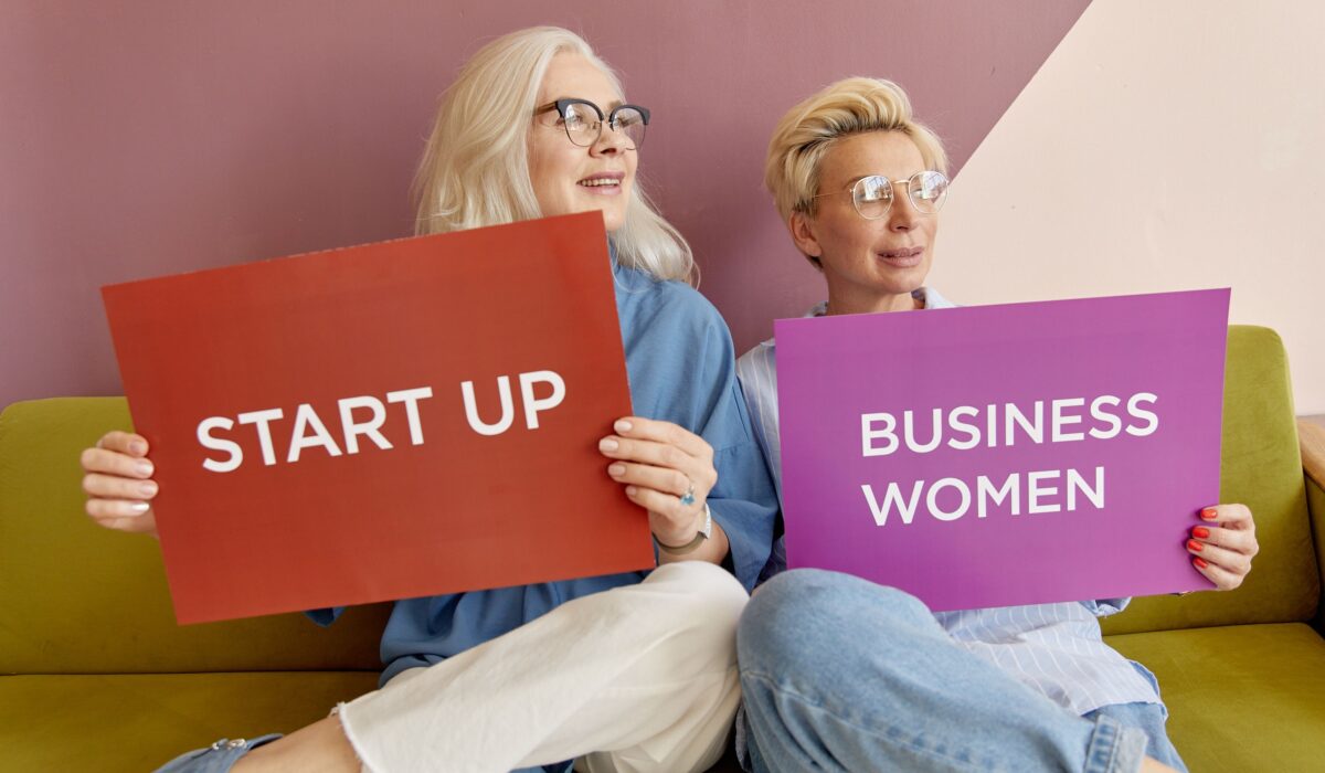 Two women on a sofa holding signs promoting startup and business women. — Photo by Darina Belonogova on Pexels